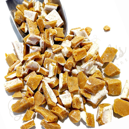 Desert Delights Grogg Nogg caramelized Eggnog peanut brittle candy in a pile with a scoop on a white background