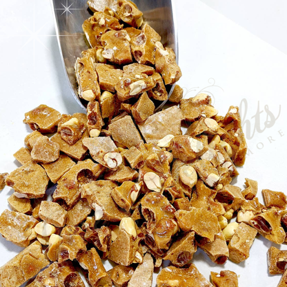 Candied jalapeno peanut brittle candy with a metal scoop on a white background
